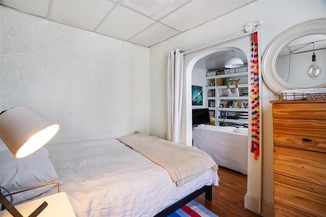 bedroom featuring a drop ceiling and wood finished floors