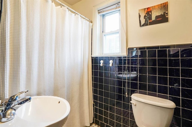 full bathroom featuring a sink, tile walls, a wainscoted wall, and toilet