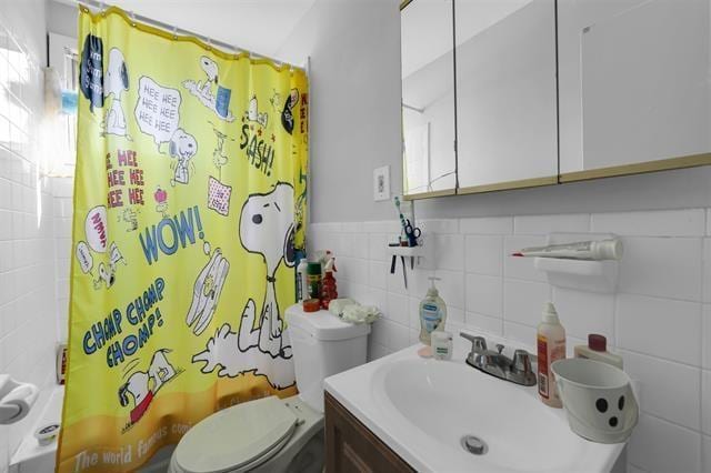 full bathroom with toilet, tile walls, shower / bath combo, and vanity