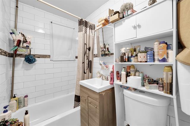 bathroom with vanity, shower / bath combo with shower curtain, and toilet