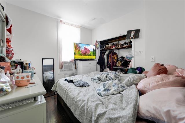 bedroom featuring dark wood-style flooring, cooling unit, and a closet