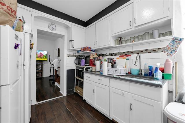 kitchen featuring decorative backsplash, open shelves, dark wood finished floors, a sink, and freestanding refrigerator