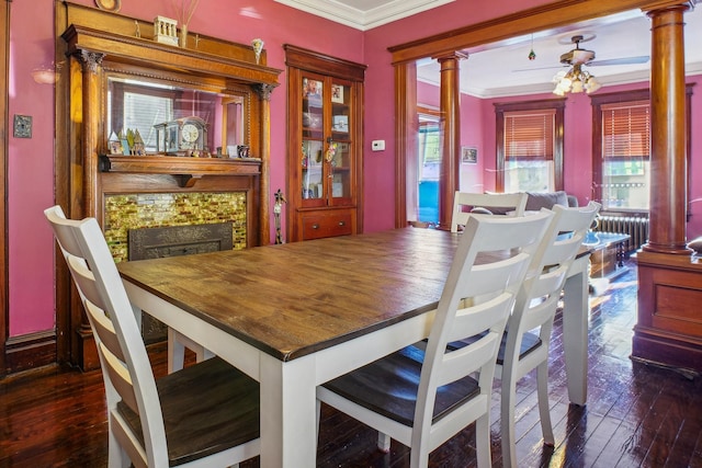 dining area featuring crown molding, decorative columns, dark wood-type flooring, and a fireplace