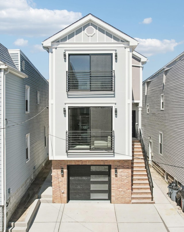 27 E 16th St, Bayonne, NJ 07002 - view of front facade featuring stairs, a balcony, a garage, brick siding, and driveway