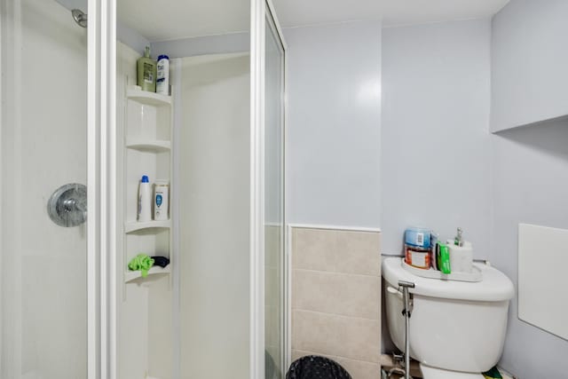 full bath featuring toilet, tile walls, and a shower stall