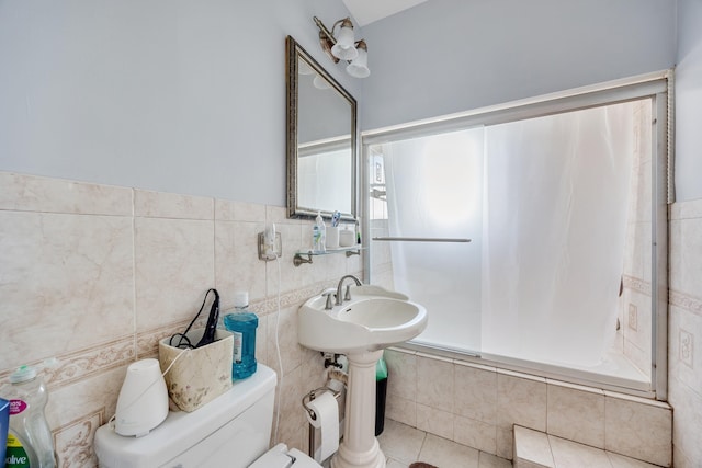 full bath featuring a sink, tile walls, toilet, tiled shower / bath, and tile patterned floors