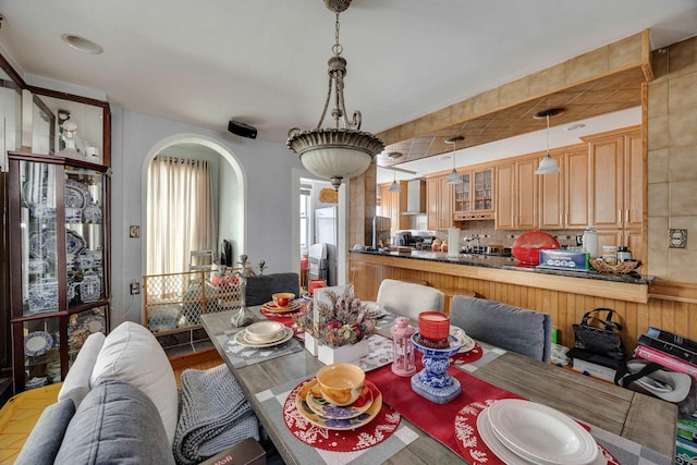 dining space featuring wood finished floors and arched walkways