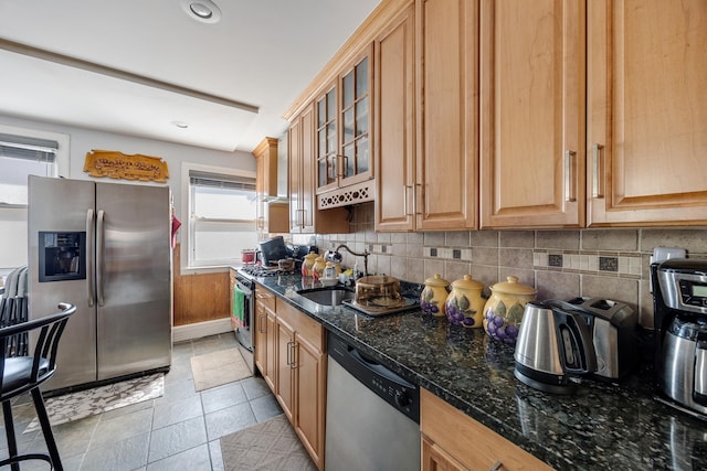 kitchen with tasteful backsplash, stainless steel appliances, glass insert cabinets, and dark stone counters