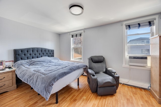 bedroom featuring cooling unit, light wood-style floors, and a baseboard heating unit