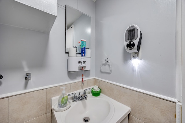 bathroom featuring tile walls, wainscoting, and a sink