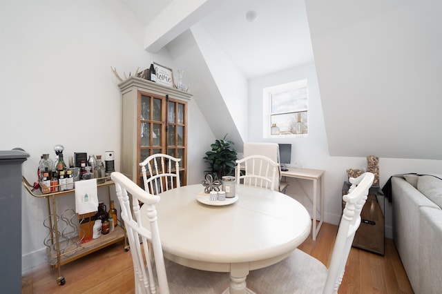 dining area with vaulted ceiling and light hardwood / wood-style flooring