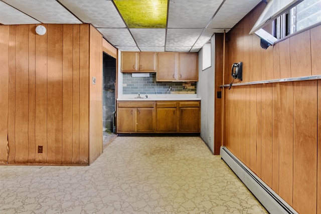 134 W 25th St, Bayonne, NJ 07002 - kitchen featuring a baseboard heating unit, wooden walls, light floors, brown cabinets, and tasteful backsplash