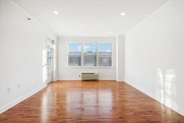 unfurnished room featuring a wall unit AC, recessed lighting, baseboards, hardwood / wood-style floors, and crown molding