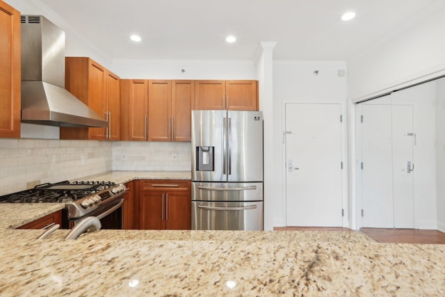 kitchen featuring decorative backsplash, brown cabinetry, light stone countertops, range hood, and stainless steel appliances