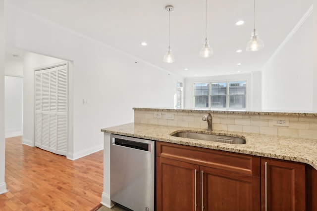 kitchen featuring light wood finished floors, hanging light fixtures, decorative backsplash, a sink, and dishwasher