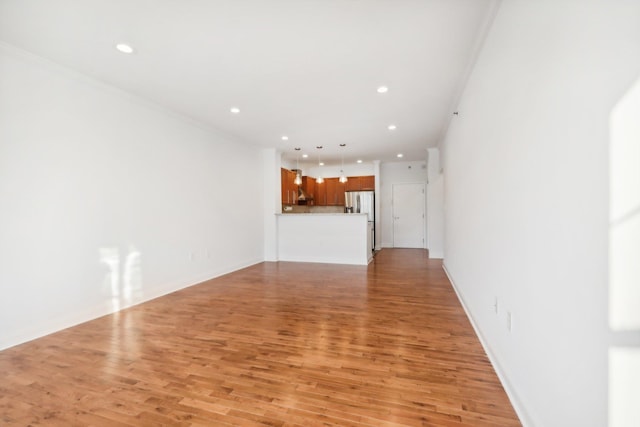 unfurnished living room featuring crown molding, light wood finished floors, baseboards, and recessed lighting