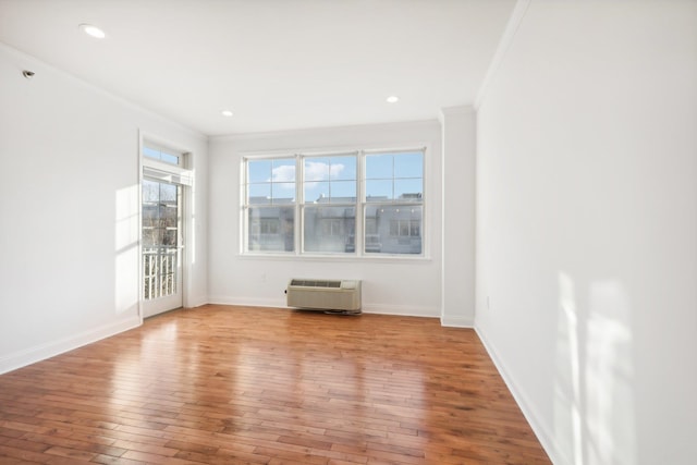 empty room with crown molding, recessed lighting, hardwood / wood-style floors, a wall mounted air conditioner, and baseboards