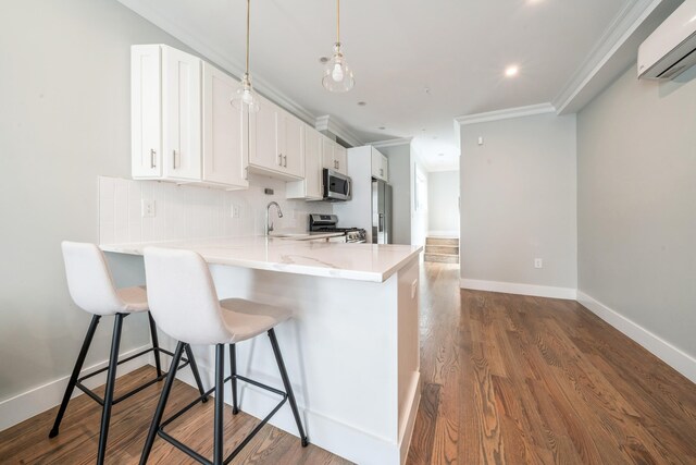 kitchen featuring stainless steel appliances, kitchen peninsula, crown molding, white cabinets, and an AC wall unit