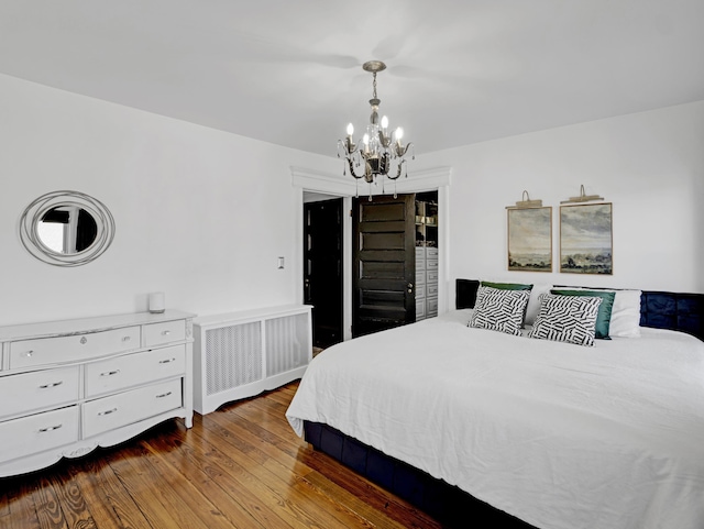 bedroom with a notable chandelier, wood finished floors, and radiator