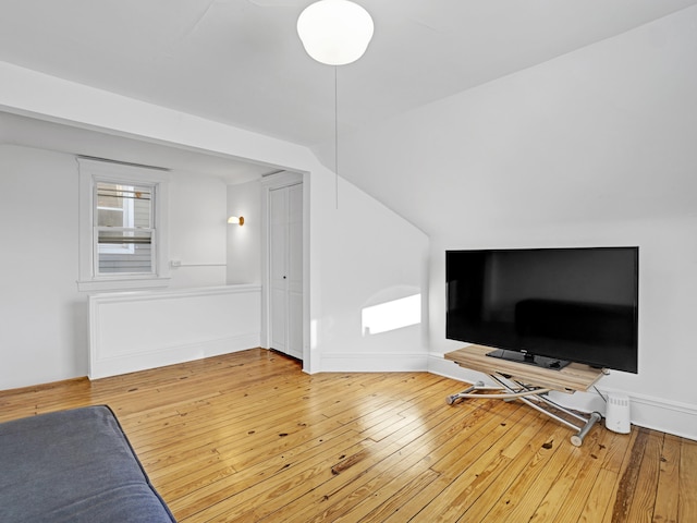 living area featuring vaulted ceiling, wood finished floors, and baseboards