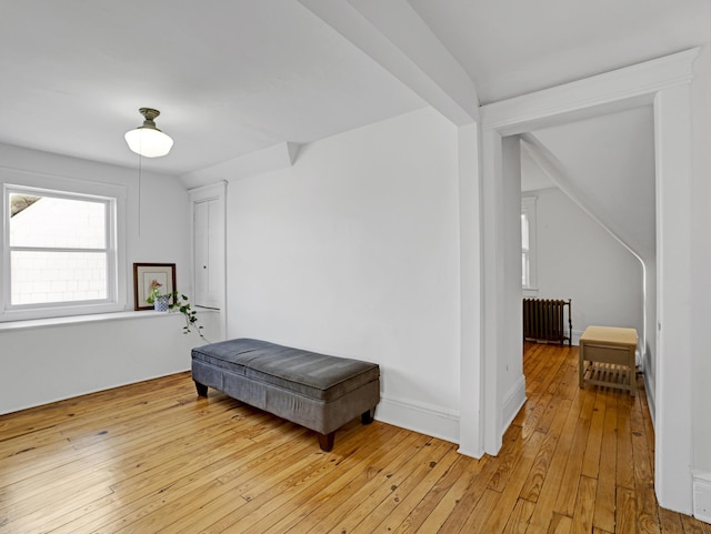 interior space with light wood-style floors, lofted ceiling, baseboards, and radiator heating unit