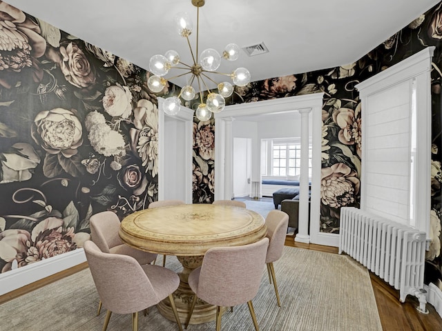 dining room with baseboards, wallpapered walls, wood finished floors, and radiator