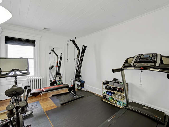 workout room featuring radiator, baseboards, visible vents, and wood finished floors