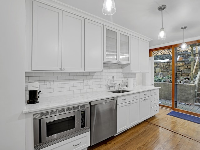 kitchen with stainless steel appliances, white cabinetry, a sink, and hanging light fixtures