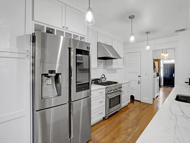 kitchen featuring stainless steel appliances, white cabinetry, under cabinet range hood, and light stone counters