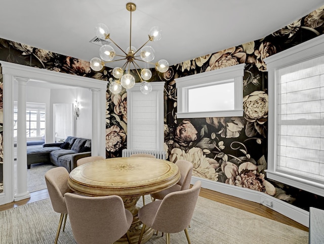 dining area with wallpapered walls, baseboards, visible vents, wood finished floors, and ornate columns