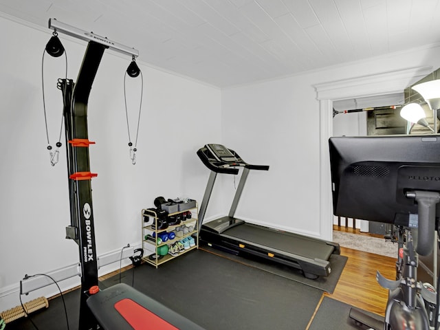 exercise room with crown molding, baseboards, and wood finished floors