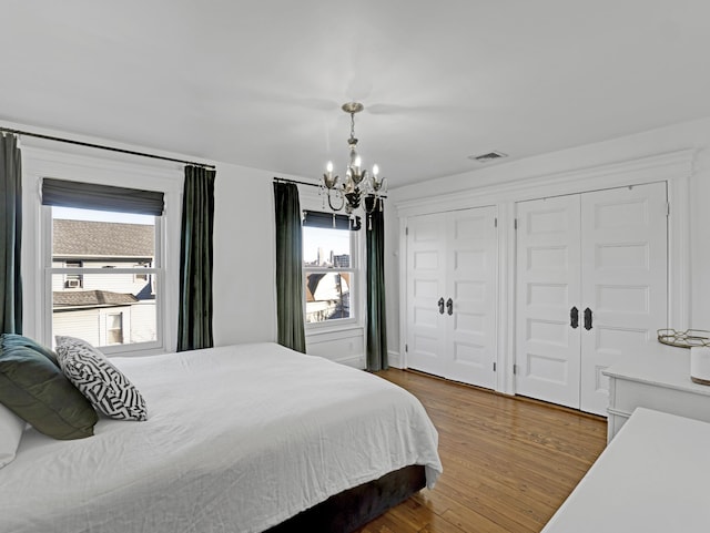 bedroom featuring dark wood-type flooring, multiple windows, two closets, and visible vents