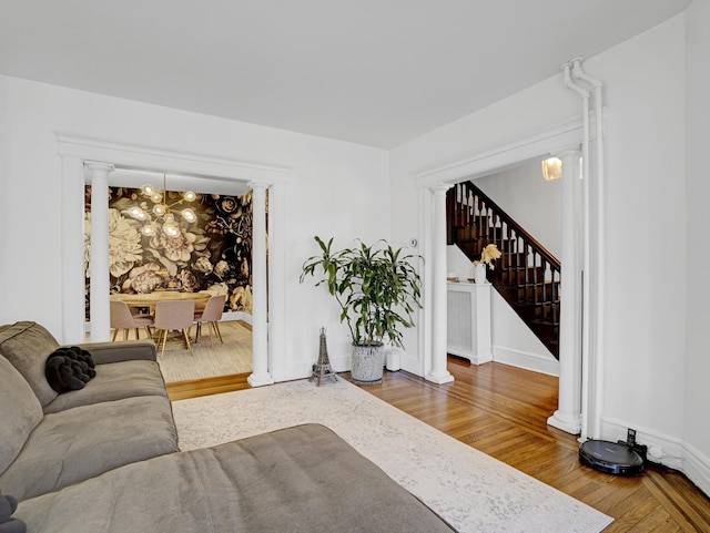 living area featuring ornate columns, stairway, and wood finished floors