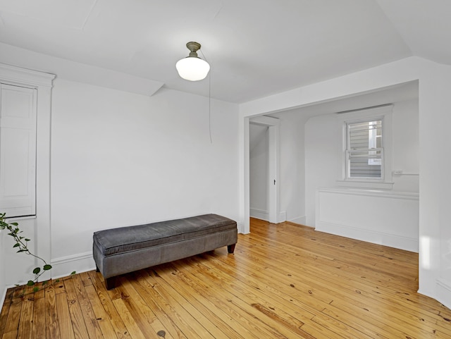 living area featuring light wood-type flooring, lofted ceiling, and baseboards