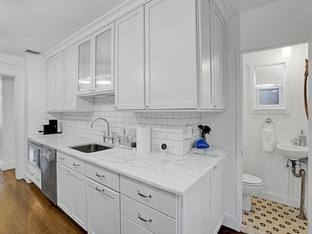 kitchen featuring light stone counters, stainless steel appliances, backsplash, white cabinetry, and a sink