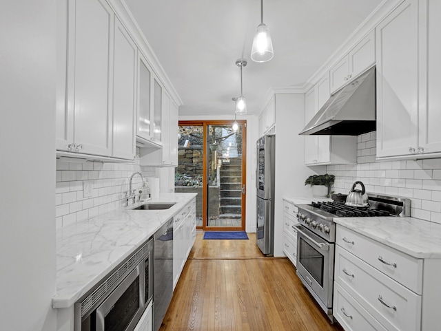 kitchen with appliances with stainless steel finishes, decorative light fixtures, under cabinet range hood, white cabinetry, and a sink