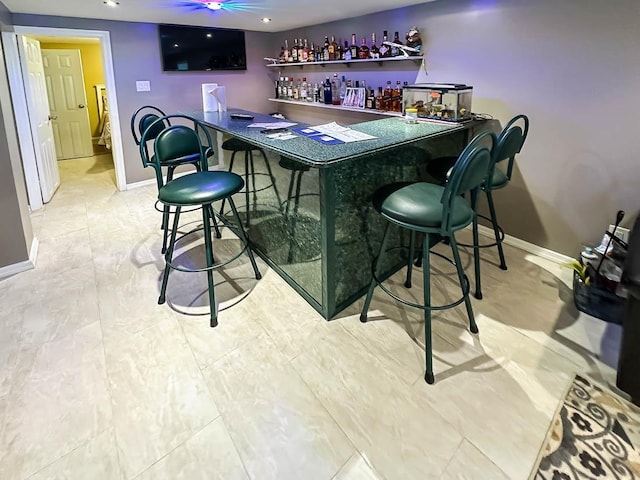 bar featuring a dry bar, a ceiling fan, and baseboards