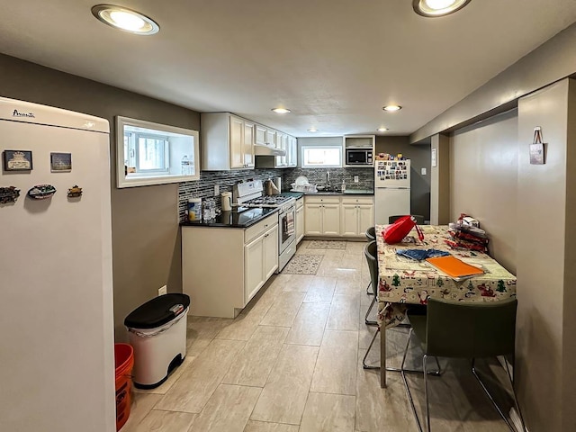 kitchen featuring freestanding refrigerator, stainless steel microwave, backsplash, and range with gas cooktop