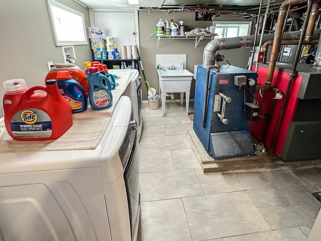 laundry room featuring washing machine and dryer, a heating unit, a sink, and tile patterned floors