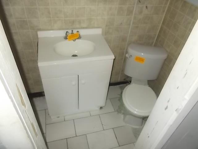 bathroom with vanity, toilet, and tile walls