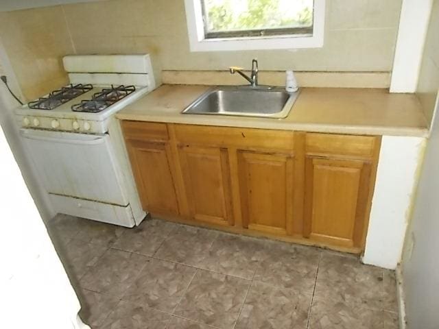 kitchen with sink, white gas stove, and light tile patterned floors