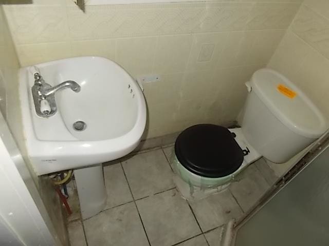 bathroom featuring tile walls, tile patterned flooring, and toilet