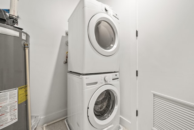 clothes washing area featuring stacked washing maching and dryer and water heater