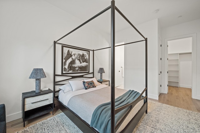 bedroom with a walk in closet, a closet, and hardwood / wood-style floors