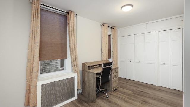 office area with radiator heating unit and hardwood / wood-style flooring