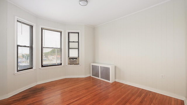 empty room featuring radiator heating unit, wood-type flooring, cooling unit, and crown molding