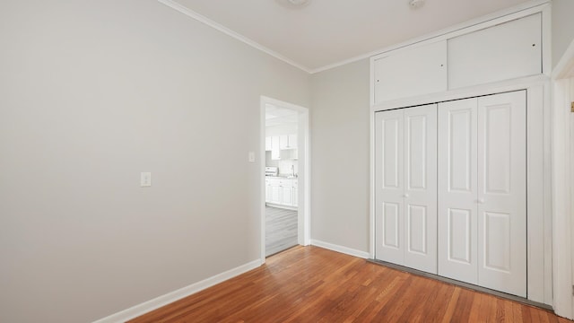 unfurnished bedroom with hardwood / wood-style flooring, a closet, and ornamental molding