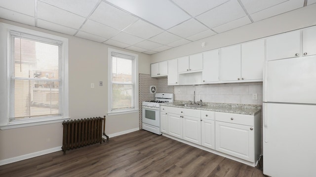 kitchen with sink, white appliances, radiator heating unit, white cabinets, and dark hardwood / wood-style flooring