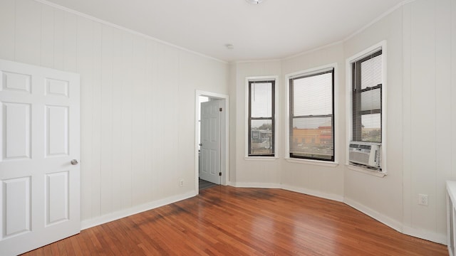 unfurnished room featuring hardwood / wood-style flooring, cooling unit, and ornamental molding