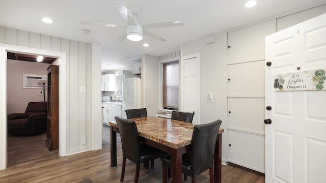 dining area featuring ceiling fan, dark hardwood / wood-style floors, sink, and a wall mounted air conditioner